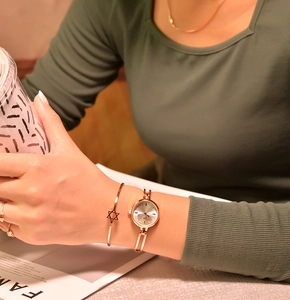Rose gold quartz watch with a matching hexagram star charm bracelet on a female wrist