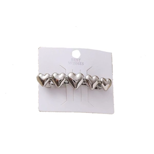 Silver metallic hair clip featuring five hearts on a white display card