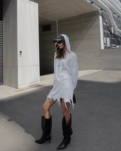 Détail de l'ensemble en maille blanche avec capuche, jupe et finitions effilochées
