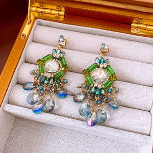 Detailed close-up of vintage gold tassel earrings with green gems and blue teardrop beads