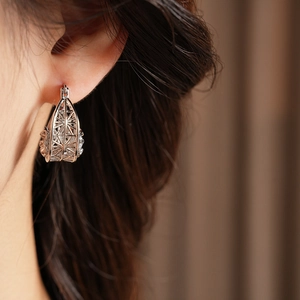 Close-up of model wearing silver hollow geometric cage earrings in a minimalist style