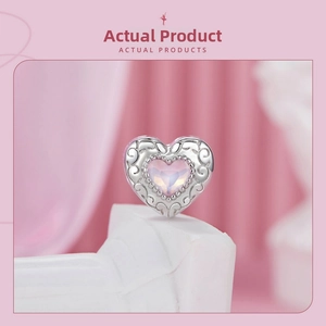 Detail of s925 silver heart bead featuring pink gemstone and ornate scroll engravings