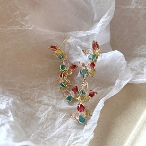 Detailed macro view of long butterfly earrings with colorful zircons on gold metal