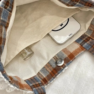 Detail view of plaid wool tote bag interior with magnetic closure and white lace trim