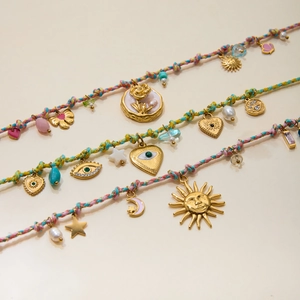 Macro shot of colorful woven bracelets featuring gold charms, pearls, and mixed beads detail