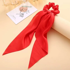 Close-up of elegant red satin ribbon hair scrunchie on a decorative beige display
