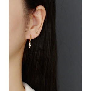 Detailed macro shot of a gold lightning bolt earring set with sparkling zircons