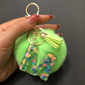 Detailed macro view of green pompom keychain with clear resin heart sequin letter A
