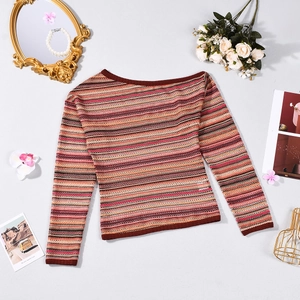 Flat lay of striped knit long sleeve top with pearl necklace and decorative floral props