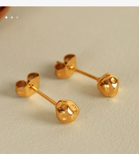 Macro shot of gold-plated irregular geometric stud earrings with hammered metal texture