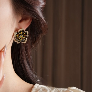 Vintage gold flower earrings with orange crystals worn by a model in a close-up shot