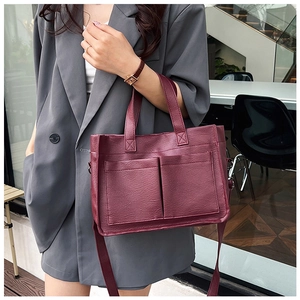 Close-up of a burgundy PU leather tote bag with functional double front pockets
