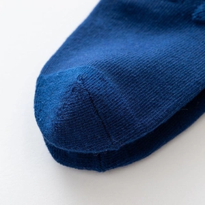 Close-up of seamless toe stitching on dark blue knit princess style baby socks