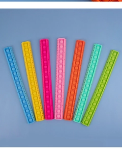 Detailed set of seven colorful silicone pop fidget rulers arranged on blue background