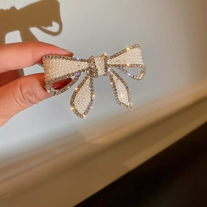 Gros plan sur la barrette à nœud avec perles et strass étincelants et finition métal