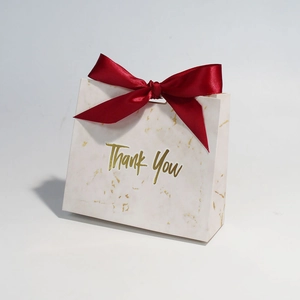 Detailed view of marble pattern gift bag with a red ribbon bow and gold Thank You text