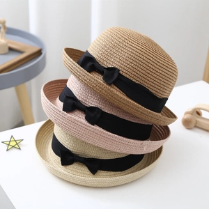 Trio of children's woven straw sun hats with black ribbons and elegant bows in soft colors