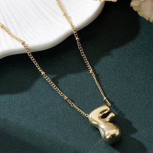 Macro shot of polished gold balloon letter F pendant on a delicate chain necklace
