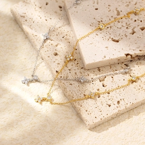 Detail of silver and gold layered necklaces with sparkling clover charms and zircons