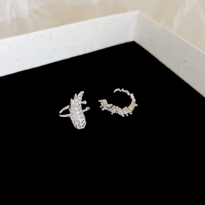 Close-up of silver zircon wing ear cuff and pearl earrings on black velvet background