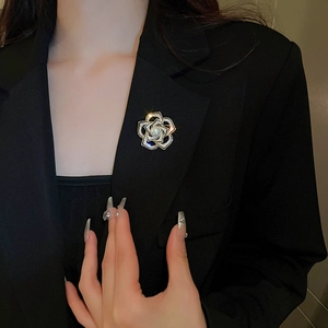 Détail macro d'une broche camélia avec zircon et perle sur revers de veste noir