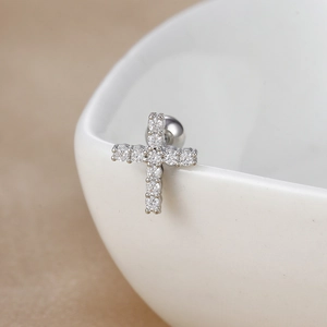 Macro detail of silver cross stud earring with zircon stones on a ceramic bowl edge