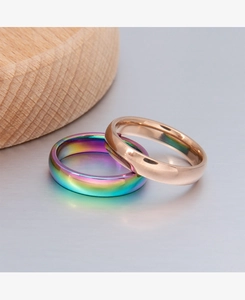 Close-up of 4mm polished rose gold and rainbow titanium steel rings on metallic surface