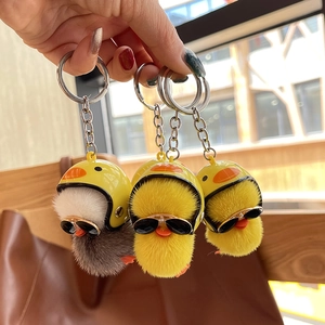 Three cute plush yellow duck keychains with mini helmets and sunglasses held in hand