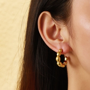Close-up of gold-plated beaded hoop earrings in high-polished stainless steel