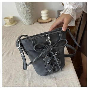 Détail du sac seau en denim gris vintage avec lacets et œillets métalliques stylés