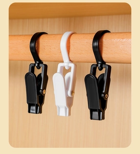 Detail of white and black multi-purpose plastic rotating hooks hanging on a wooden rod