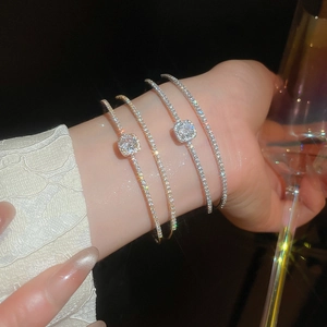 Close-up of sparkling zircon bow double-layered open bracelets in gold and silver finishes