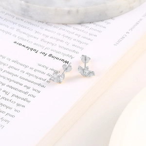 Macro detail of silver S925 leaf earrings with marquise-cut zircons on a marble tray