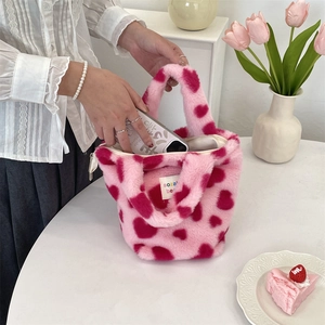 Detail showing plush pink handbag with red hearts and mobile phone inside for size