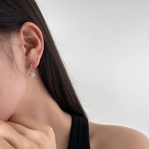 Detailed view of silver heart-shaped drop earring with zircon on a female model