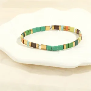 Detail of colorful Tila bead stretch bracelet with golden spacers in a shell tray