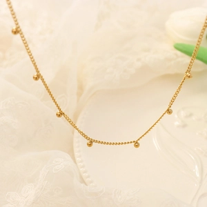 Elegant gold beaded choker necklace for women with minimalist aesthetic on white lace