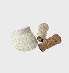 Detail showing foldable straw sun visors in beige and khaki with fringe edge design