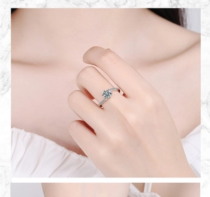 Close-up of a silver ring with a six-prong round zircon and a crisscross diamond band