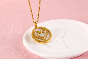 Detail of golden stainless steel necklace with double heart pendant on decorative plate