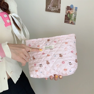 Detail of pink quilted cosmetic bag with cute bear and donut pattern held by a hand
