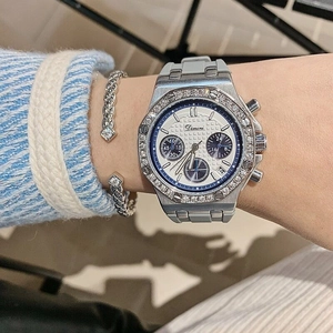 Detail view of the silver diamond bezel and white three-eye chronograph watch on wrist