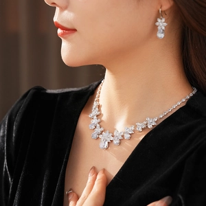 Detailed view of zircon flower necklace and teardrop earrings on model with velvet outfit