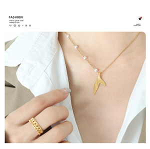 Detail of gold-plated mermaid tail pendant necklace with delicate pearls on an elegant model