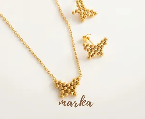 Macro shot of butterfly jewelry set with golden beaded details on a coral stand