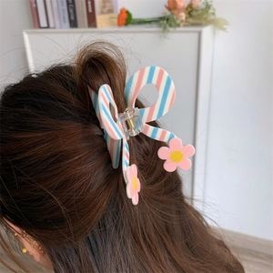 Detail of butterfly hair claw with pink blue stripes and flower accents on long hair