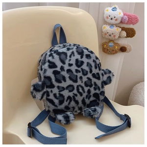 Detail of plush grey leopard print mini backpack with blue straps on a chair