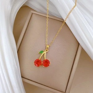 Collier à pendentif cerise dorée avec cristaux rouges sur une boîte cadeau à bijoux