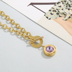 Close-up of golden chunky chain necklace with purple crystal pendant and OT buckle