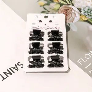 Close-up of six mini black bow-shaped hair claws on a fashion jewelry display card